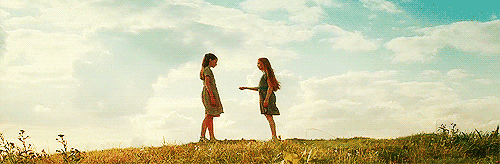 Lily and Petunia standing on a hill with a flower growing out of Lily's hand