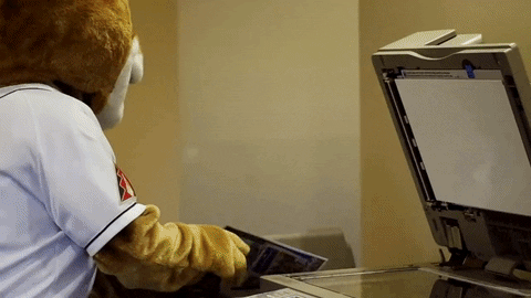 Furry in baseball kleding scant zichzelf met een kopieermachine.