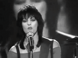 Joan Jett singing in front of a microphone.