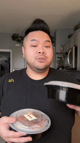 Man holding a stack of meal prep containers, looking relieved