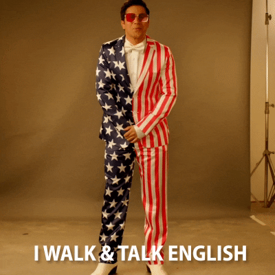 A man in a USA flag suit raising his fist to emphasize :I walk and talk English