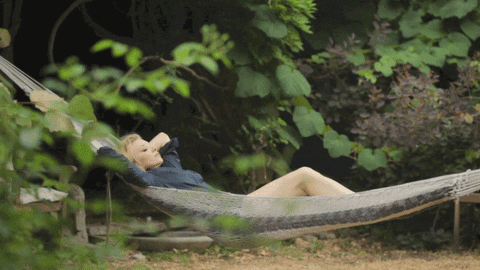 [Image description: A woman swinging in a hammock with her eyes closed, hands folded under her head.] Via Giphy