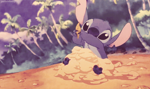 A small blue alien builds a pile of sand, then places a leaf on top and cheers.