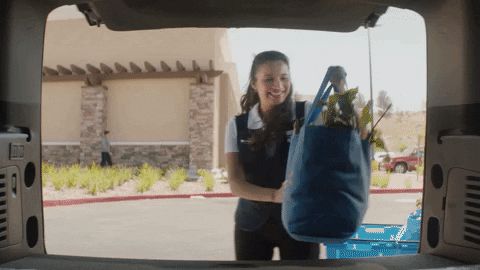 Mujer trabajadora de Walmart poniendo bolsas de compras en un carro