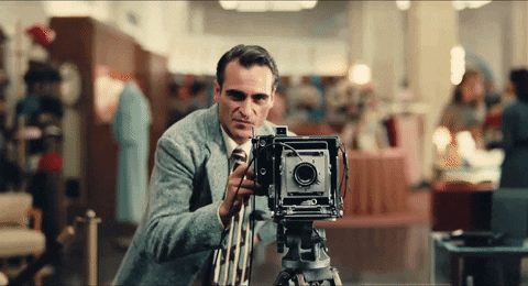 A man counts down from three as he takes a photo on an old-fashioned standing camera.