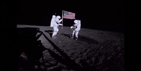 astronautas fixando a bandeira dos Estados Unidos em solo lunar