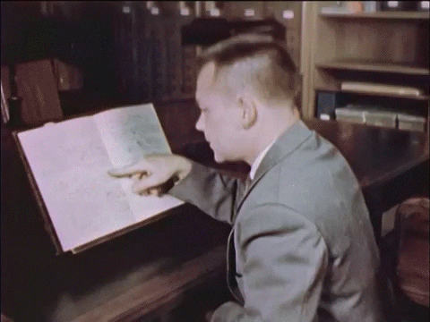Guy with a buzzcut reading a document and looking pleased