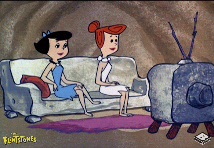 Wilma and Betty from the Flintstones sitting on a couch watching TV