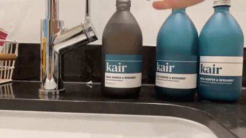 Gif of Kair's Activewear Wash bottle being picked up and poured into a basin. It is placed alongside Kair's Signature Wash and Conditioner in Wild Juniper & Bergamot