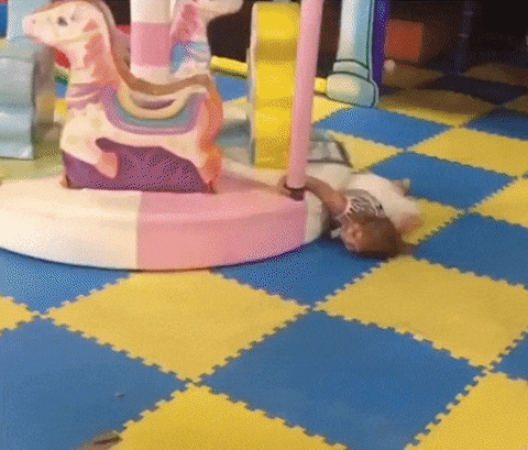 Toddler gets dragged on the ground by a child-sized merry-go-round