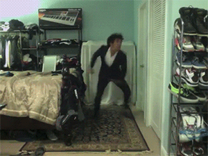 A GiF of a dancer dressed as batman doing funky dance moves in his bedroom.