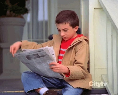 Gif de um menino lendo um jornal sentado em uma escada e levantando um dedo