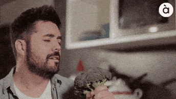 GIF con persona cantando con brocoli como microfono.