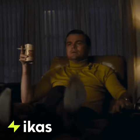 Leonardo DiCaprio pointing excitedly at a television, recognizing something familiar