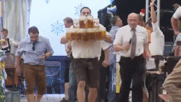 Man draagt veel enorme pinten bier naar een tafel