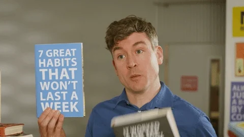 Comedian holding a fake book titled it worked for me but it won't for you