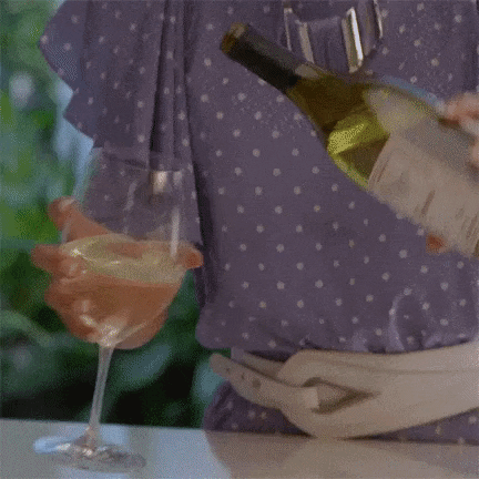 A giph of a woman pouring half a bottle of white wine into a wine glass while shaking her head, clearly displeased. 