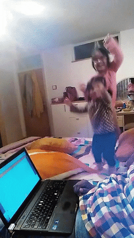 kids jumping on bed while dad tries to work