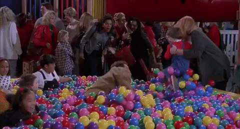 A man being hit by friends in the ball pit