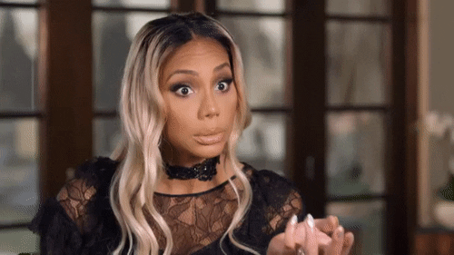 a GIF of Tamar Braxton pushing her blonde hair back and taking a sip of champagne out of a flute