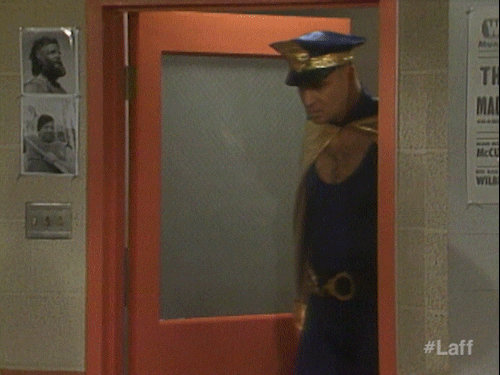 Politieman in een strak pakje en een gouden cape loopt het politiekantoor binnen.