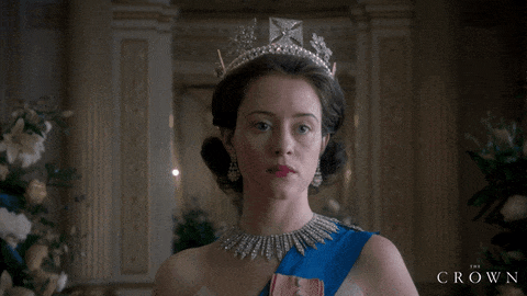 A atriz Claire Foy na pele da Rainha Elizabeth II na série The Crown. Ela usa uma coroa e um colar igualmente esbeltos.