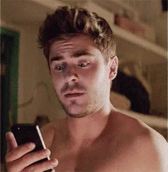 Zac Efron looking shocked at his phone