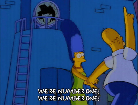 The Simpsons: Homer and Marge dance on a dock, Homer pointing up and chanting "We're number one!"