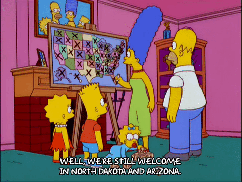 Lisa Simpson standing on stage pointing at a presentation slide
