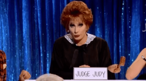 Animated GIF of Bianca del Rio, dressed as Judge Judy. She bangs her gavel on the desk in front of her. 