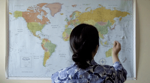 mulher marcando localização com um alfinete em um mapa na parede
