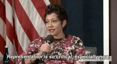 Gif of woman of color, in front of red and white stripes of US flag, speaking into a microphone and saying: "Representation is so critical, especially now."
