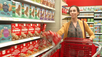 mulher passando a mão atrás de caixas que estão na prateleira de uma loja Target e derrubando todas em seu carrinho para aproveitar a promoção da Black Friday