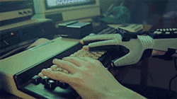 Robotic and human hand fake typing on a terminal, with code appearing quickly on the screen