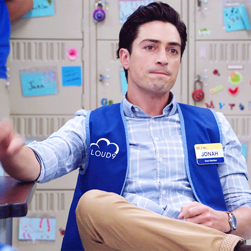 A GIF of Jonah from Superstore sitting in a chair and doing a fist pump.