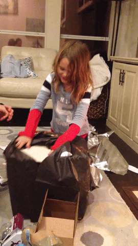 Gif with two children excited unpacking a present 