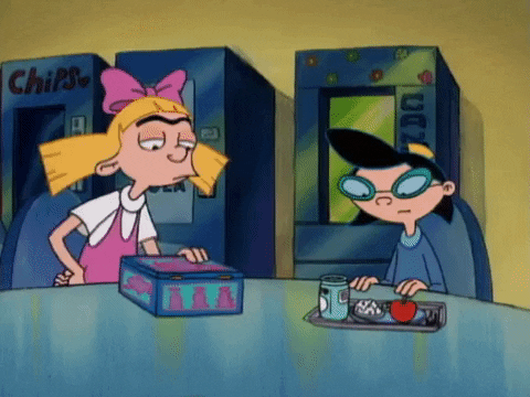two cartoon girls sitting at lunch table, one of them opening their lunch box