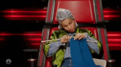 Singer, Alicia Keys sitting in a red chair knitting
