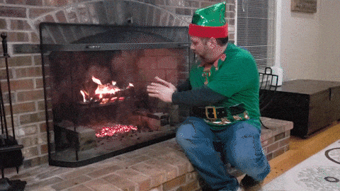 Un homme qui se réchauffe au coin du feu avec des habits de Noël