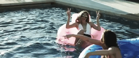 GIF of two women in a pool at a Quinceanera pool party, playing with inflatable toys