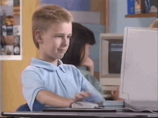 menino usando um computador antigo fazendo sinal de positivo com o dedão