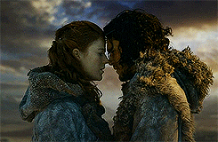 Kit and Leslie kiss as their characters in 'Game of Thrones' in front of a cloudy sky. 