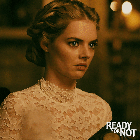 Grace (Samara Weaving) in her white wedding dress, looking down at the card she just pulled