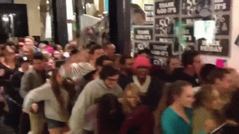 A Black Friday crowd swarming through the doors of a store to get to the Black Friday deals.