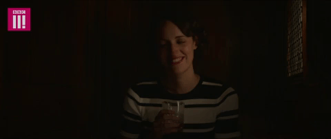 fleabag sitting in a dark confessional with a drink