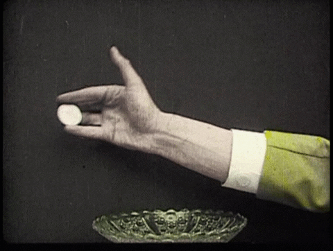 A gif with a guy doing a magic trick with a coin