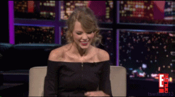 Taylor Swift laughing and covering her face with her arm.