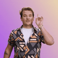 Man in a patterned shirt pointing at the camera