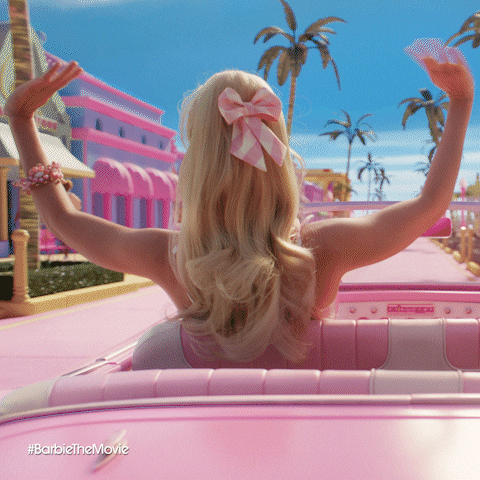GIF from barbie movie of Barbie waving to friends in Barbie Land