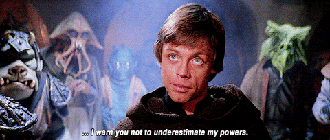 Luke Skywalker speaking to a person while standing in front of other characters. 